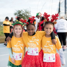Girls on the Run participant high fives running buddy at 5K  