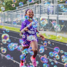 Girls on the Run participant approaching finish line with bubbles