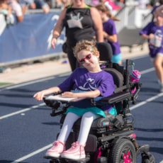 Girls on the Run participant in motorized chair on the course