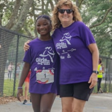 A Girls on the Run member and Coach smiling on the course